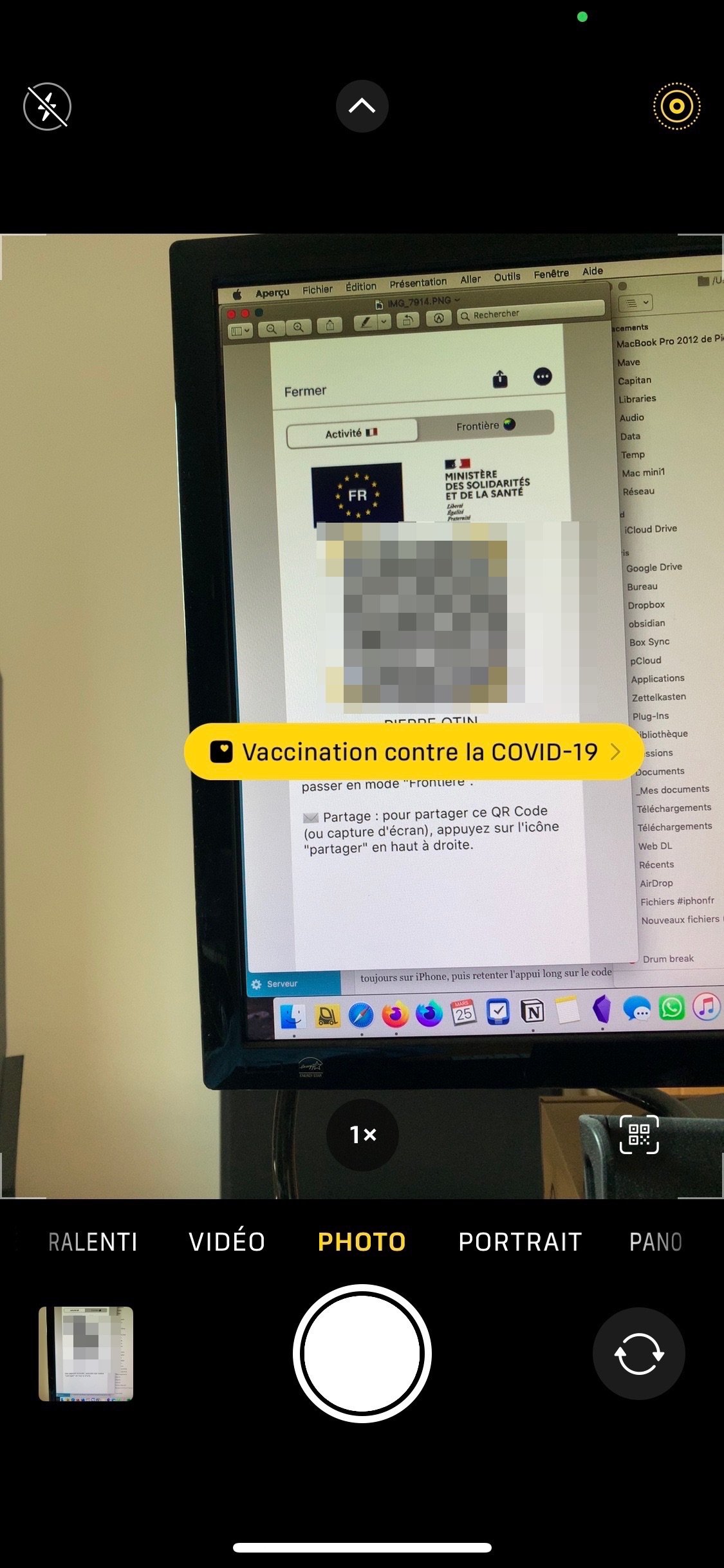 iPhone camera aiming at MacBook screen with QR code