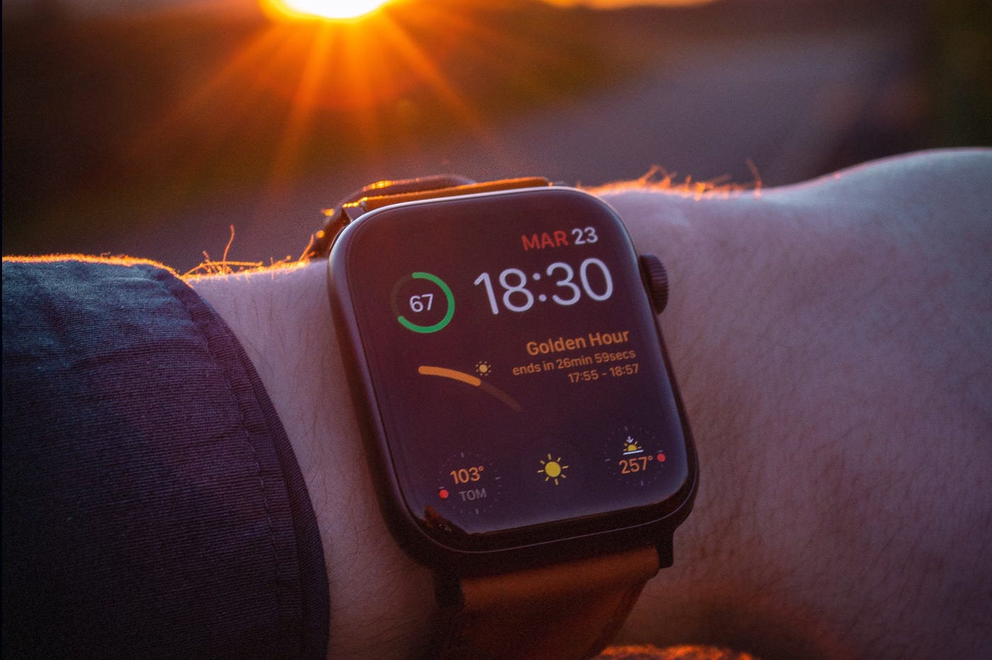 Apple Watch au poignet et soleil couchant